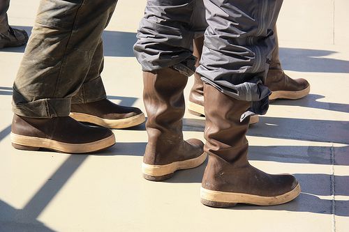 Three people standing and wearing brown Xtratuf boots, Westmark Hotels
